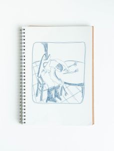 a sketchbook with an illustration of a person in cowboy boots sitting in a chair with their head on the round table next to them. there are two flowers on the table.