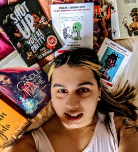 selfie image of Serena Bhandar lying down amongst books