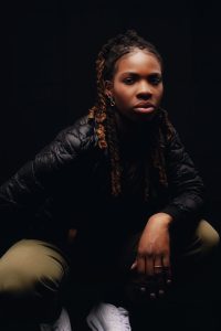 portrait photo of Haviah Mighty in a crouched stance in front of a black backdrop by Yung Yemi