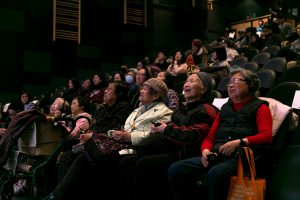 photo from the Speak My Language Launch of the audience, with the Chinese seniors sitting in the front row listening, watching, laughing.